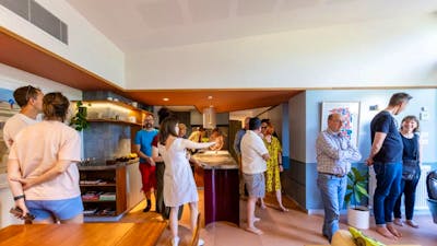 A group of people touring inside a home in the kitchen with bare feet