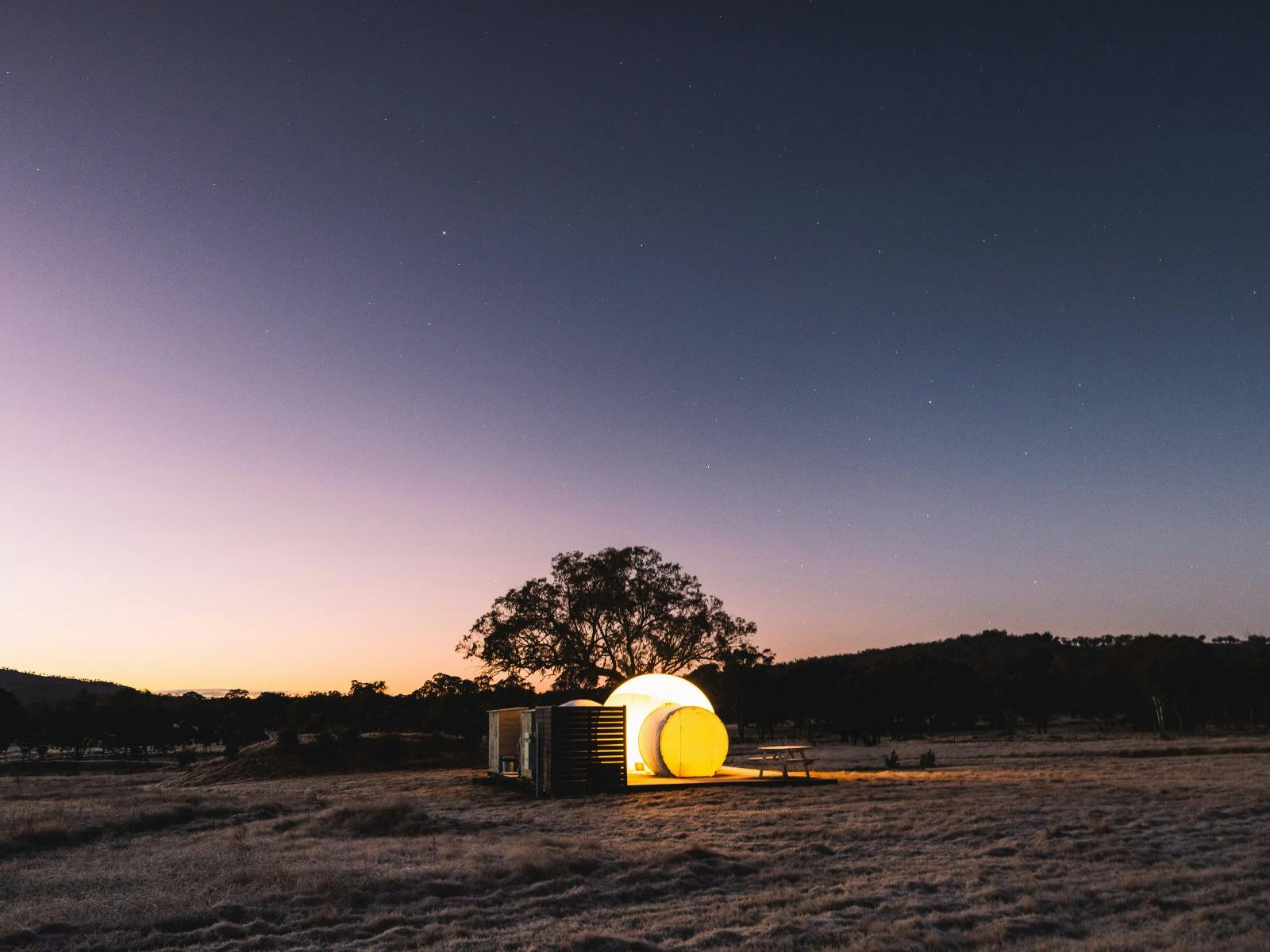 Captain Moonlite Bubbletent against a pink morning sunrise sky with stars still overhead
