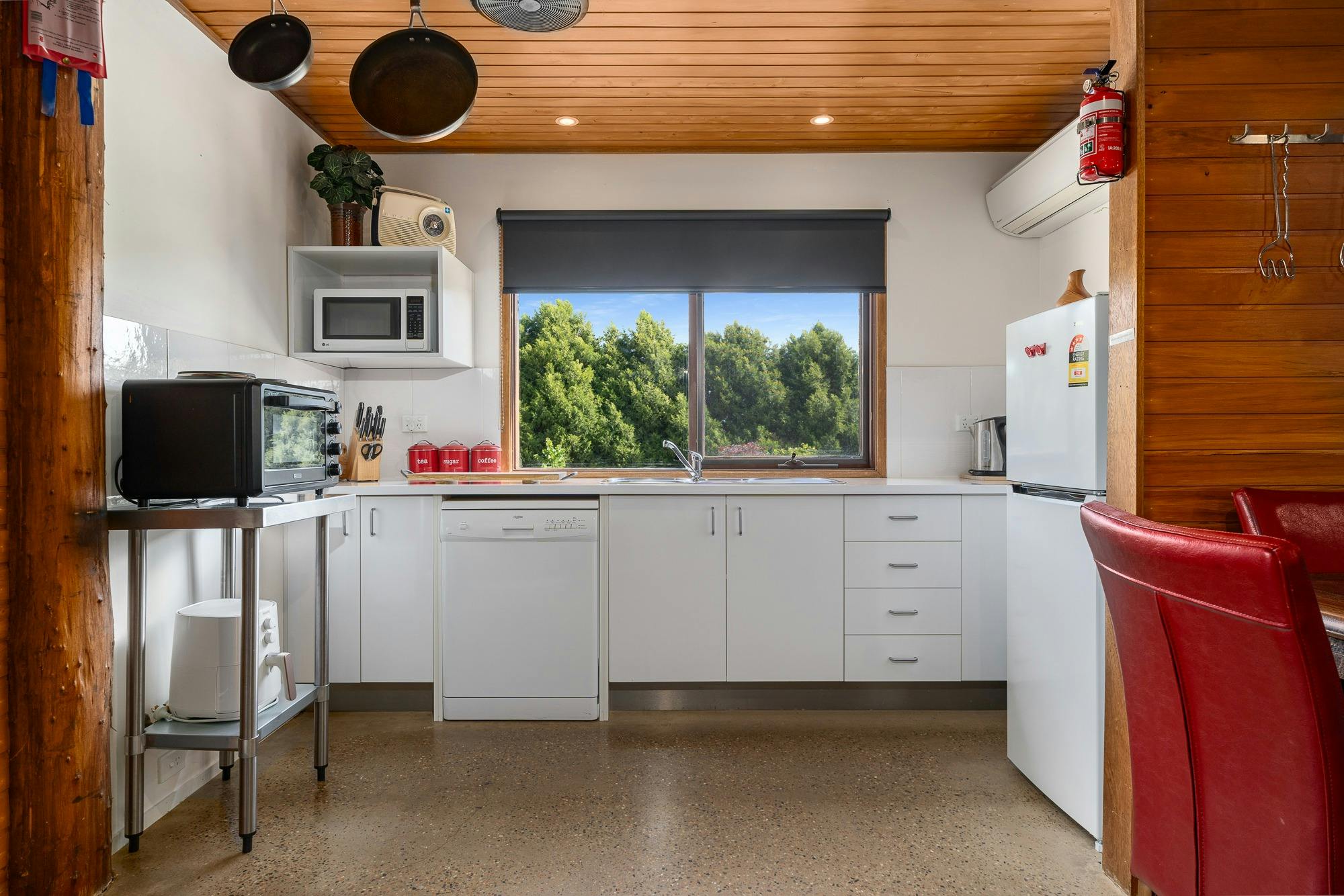 Kitchen with white cabinets, wooden ceiling and concrete flooring