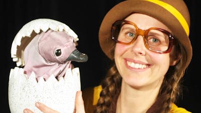 Girl with glasses holding a baby echidna puppet