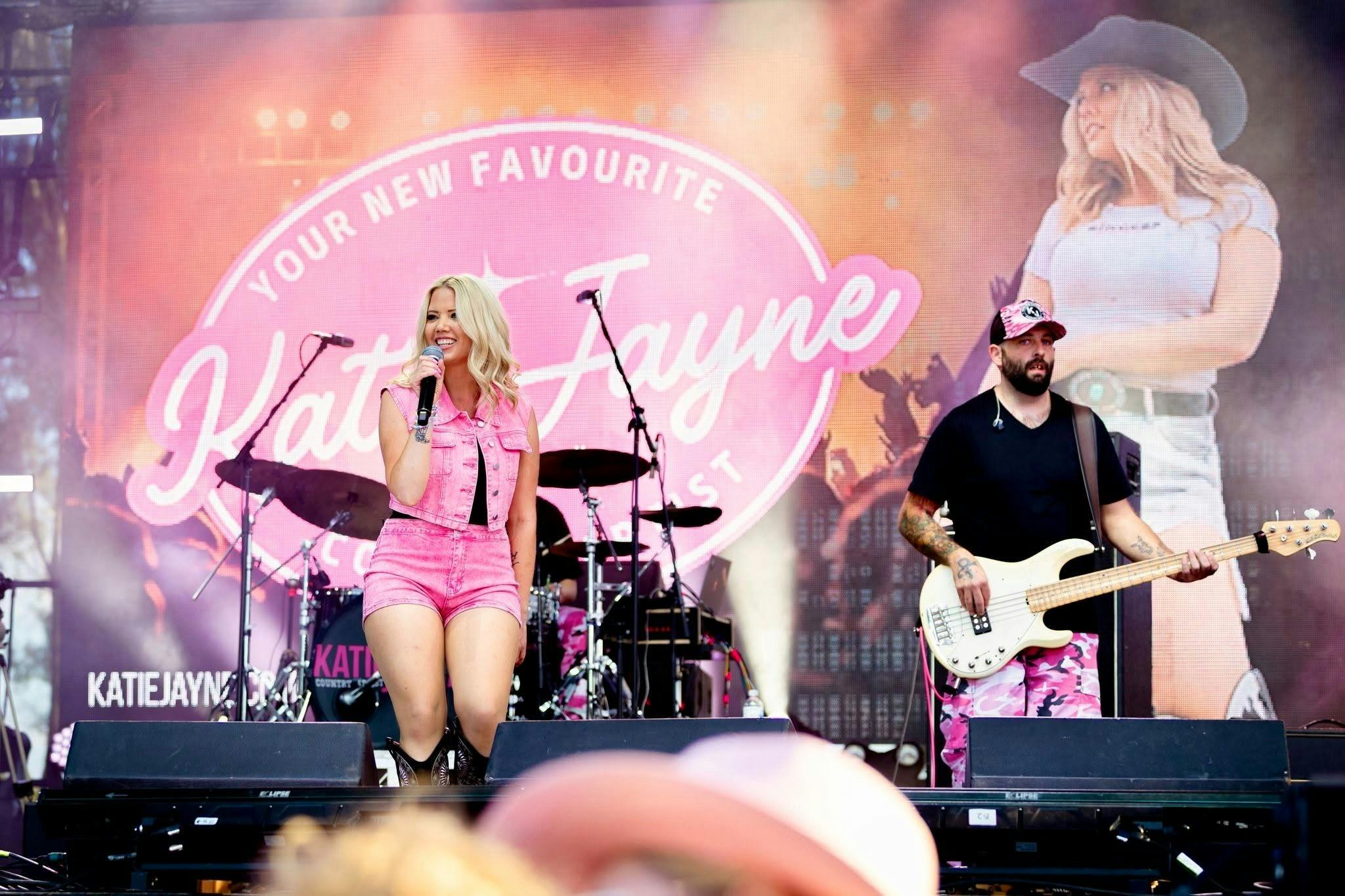 Australian country singer Katie Jayne performs live on stage, wearing a pink denim outfit and entert