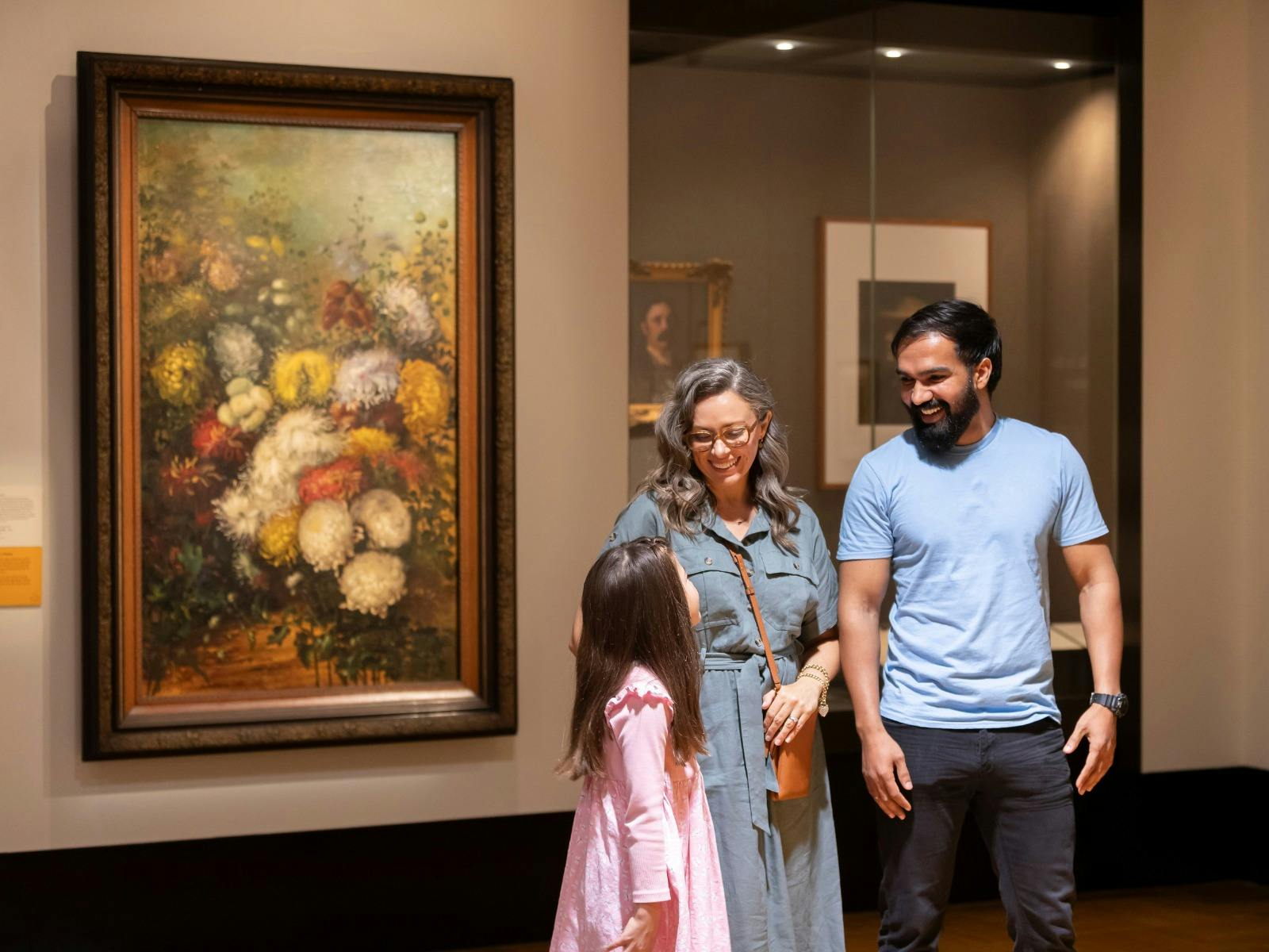 A mother, father and young daughter in an indoor exhibition space.