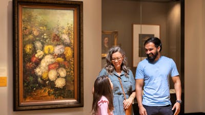 A mother, father and young daughter in an indoor exhibition space.