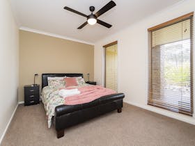 Bedrrom with queen sized bed. Two full length windows and ceiling fan. Carpeted floor