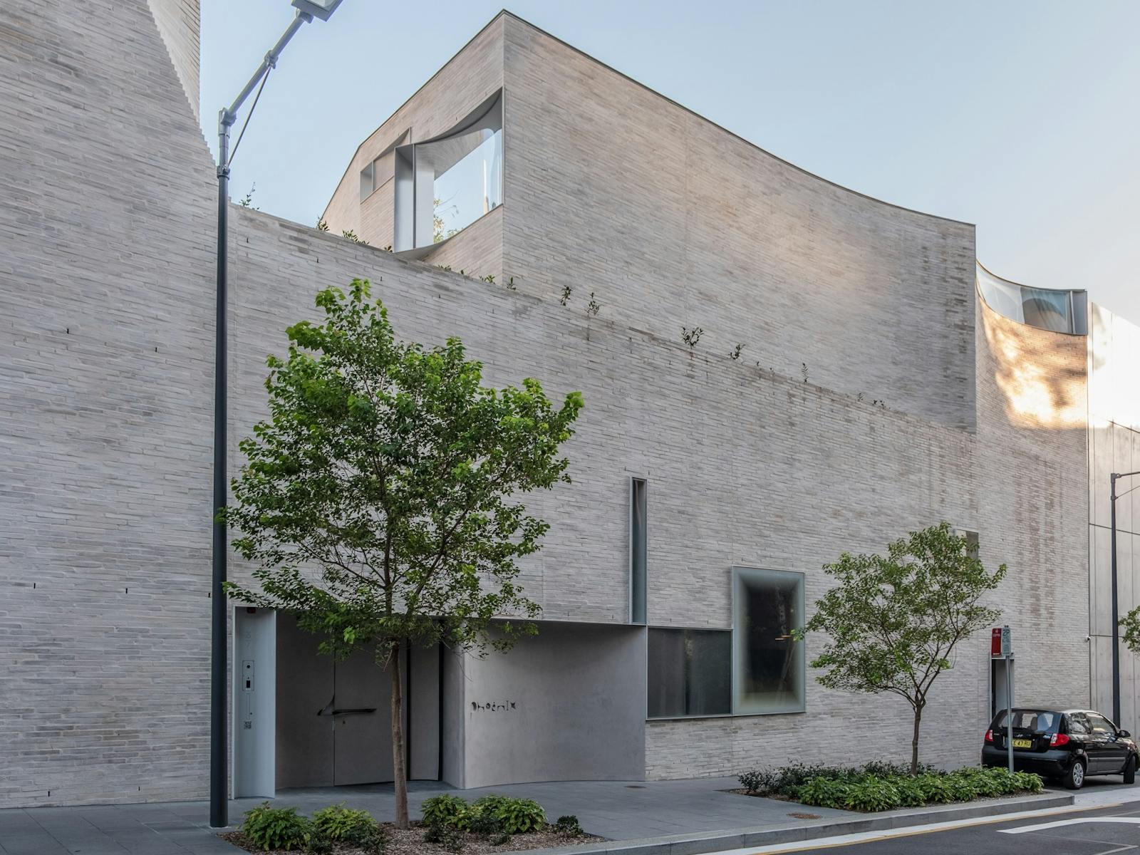 exterior Phoenix - curved white brick building with Phoenix logo on the door