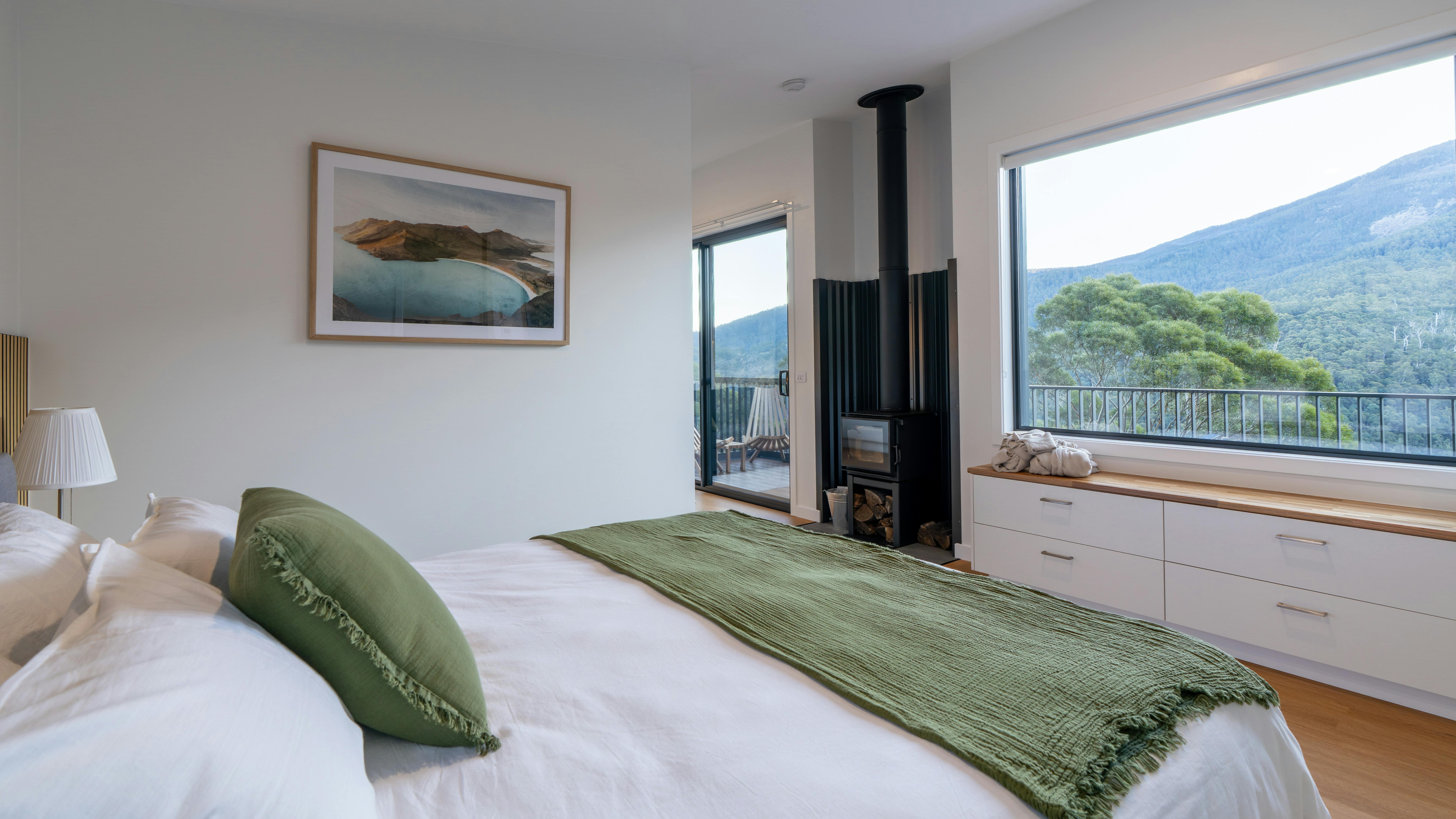 Inviting bedroom with white cotton bedding and a big window overlooking vast bushland