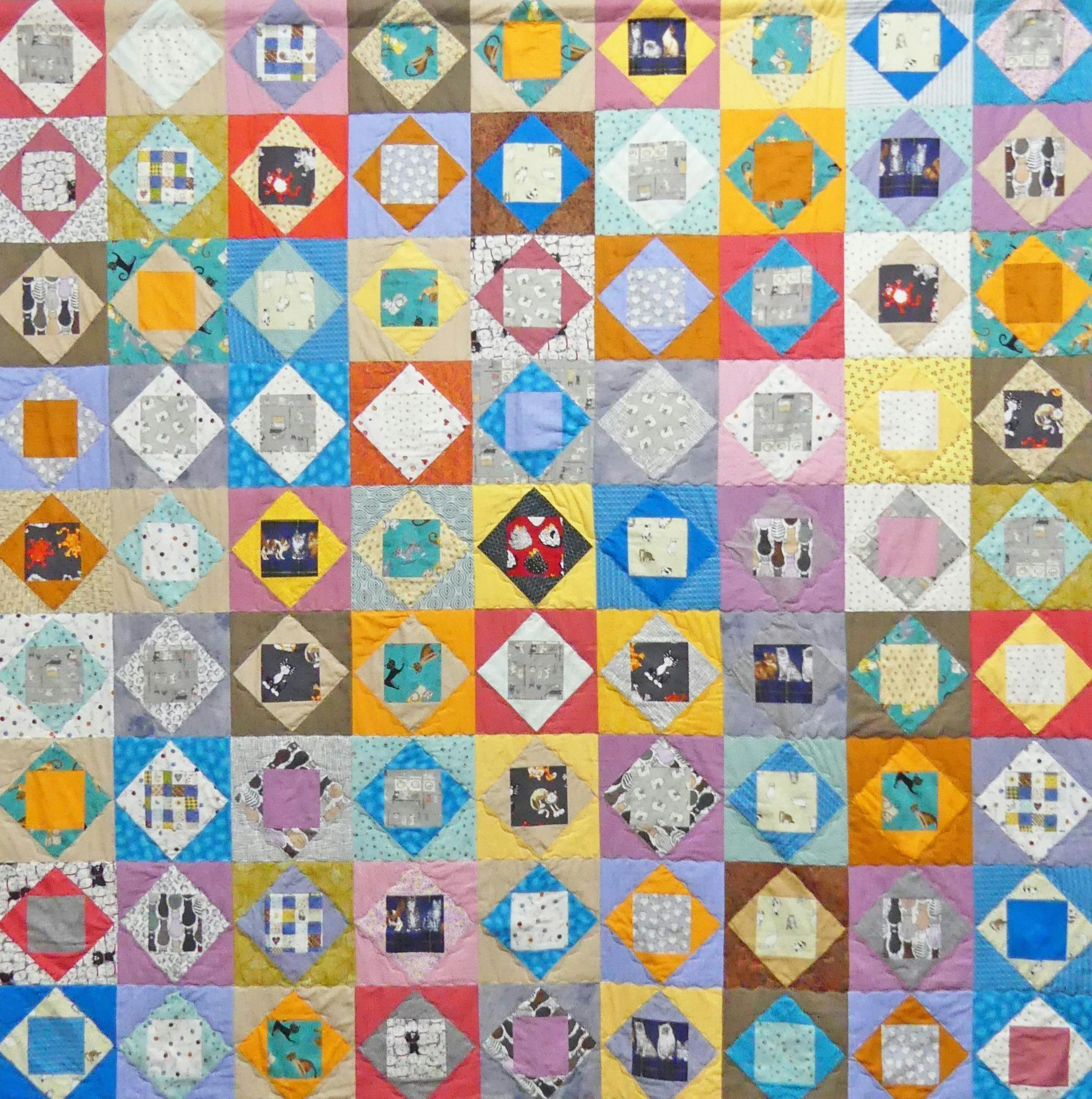 Every block has a cat in it except one. Multi-coloured quilt.