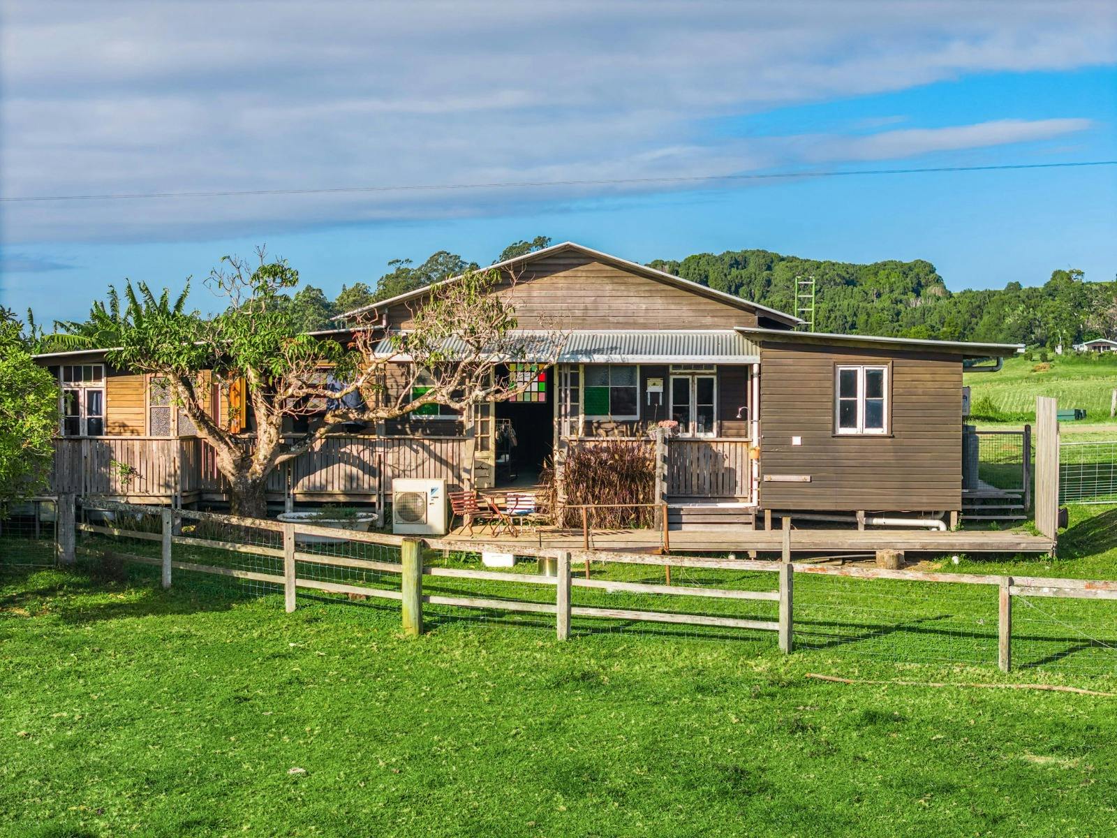 A timber dwelling on a farm with a timber fence and stained glass windows