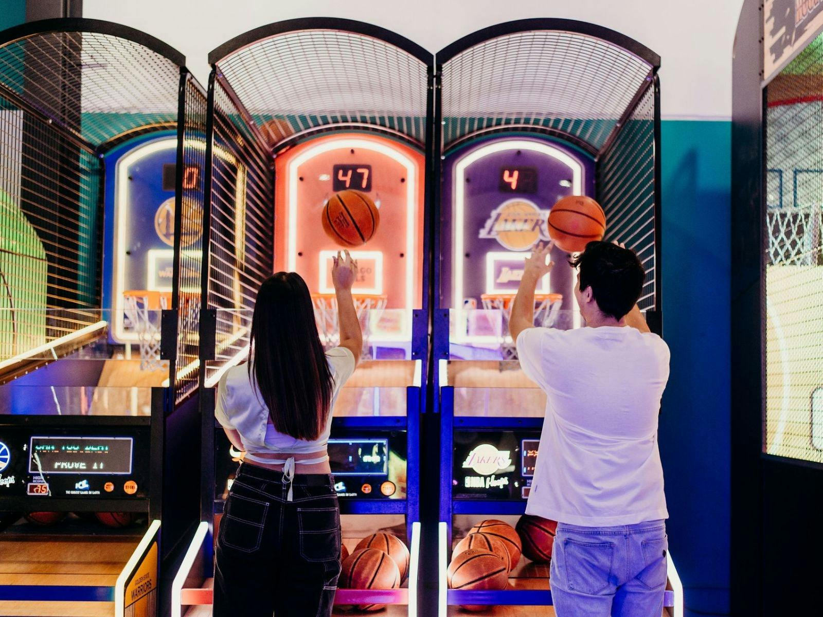 two young adults playing a basketball arcade game