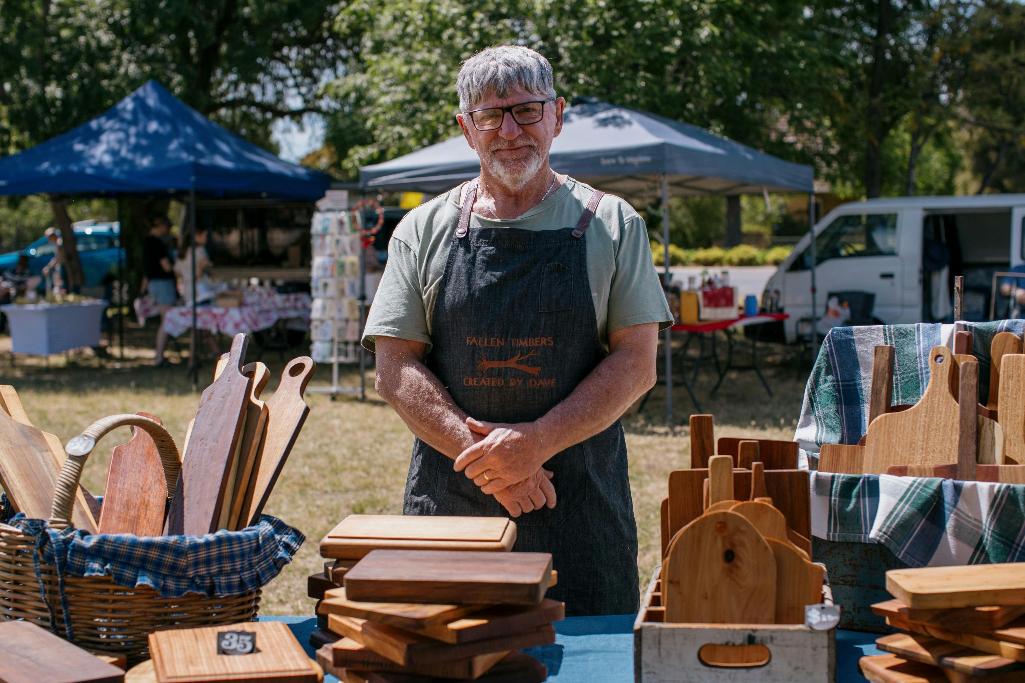 Man with black apron standing behind goods at Devenish market