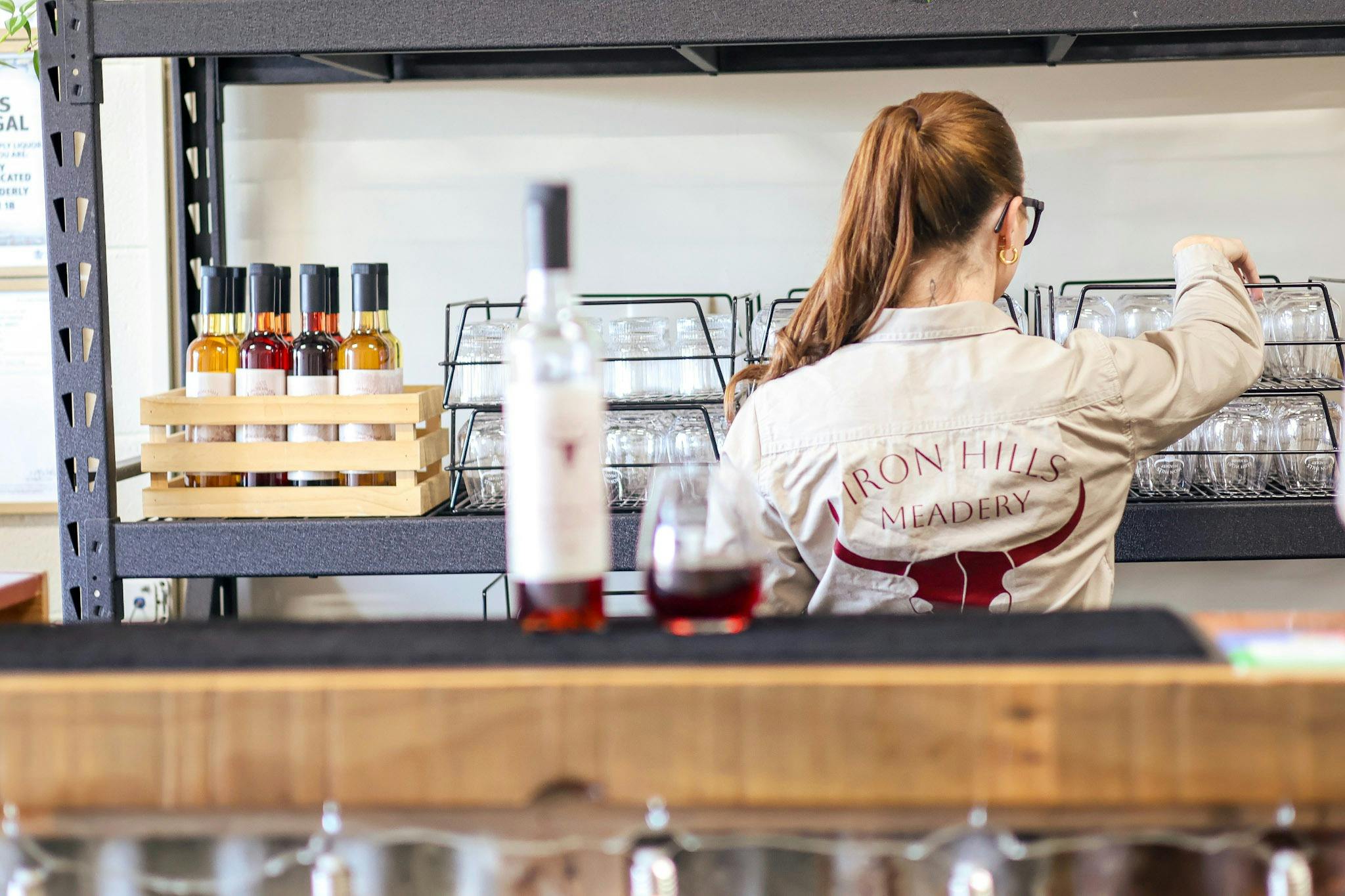 Katrina standing behind bar with mead in glass