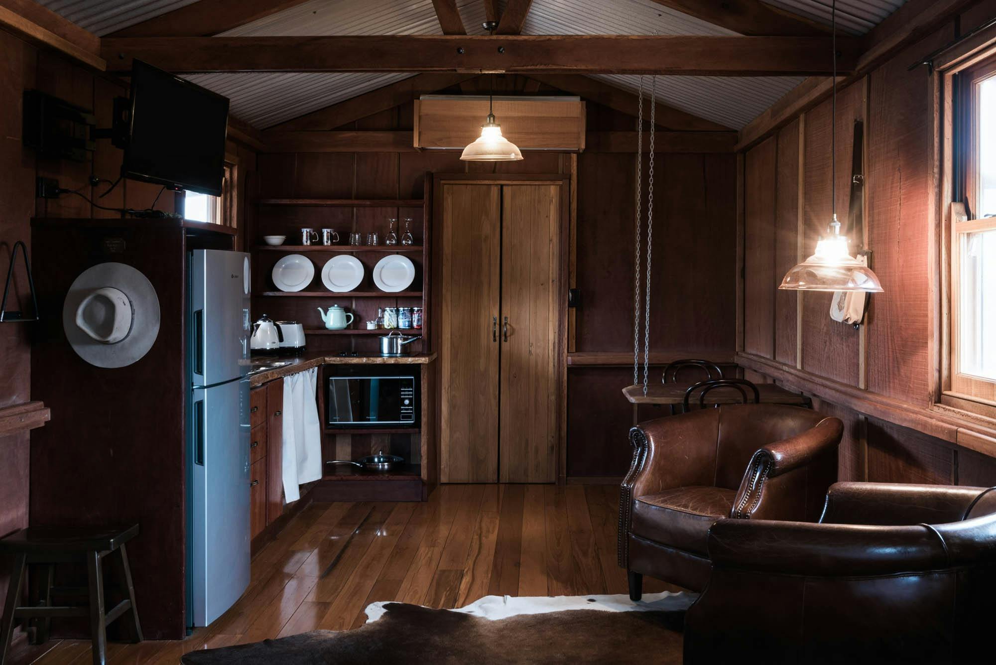 Kitchenette and sitting area inside of timber walled cabin