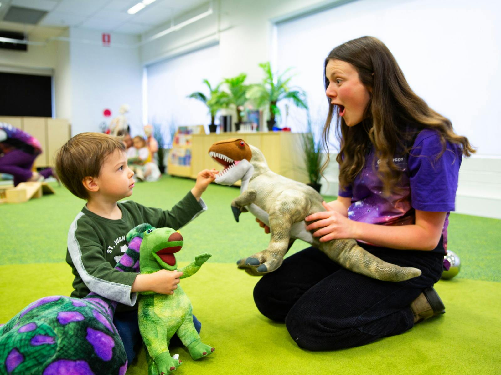 A young boy and a Questacon facilitator play with dinosaurs at Science Time