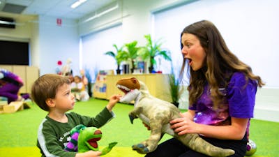 A young boy and a Questacon facilitator play with dinosaurs at Science Time