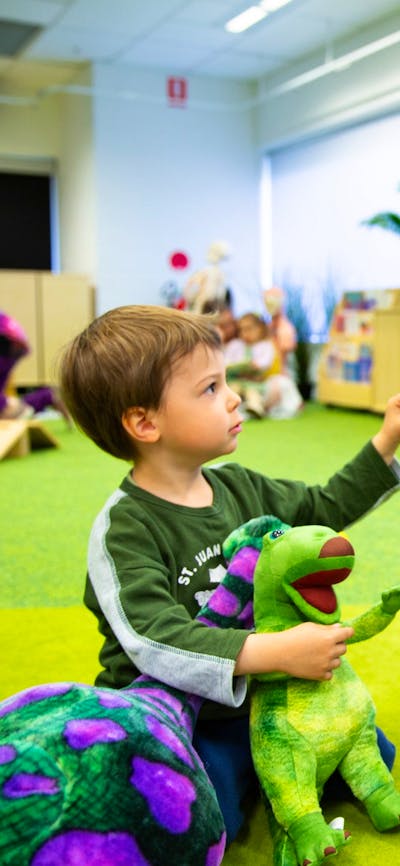 A young boy and a Questacon facilitator play with dinosaurs at Science Time