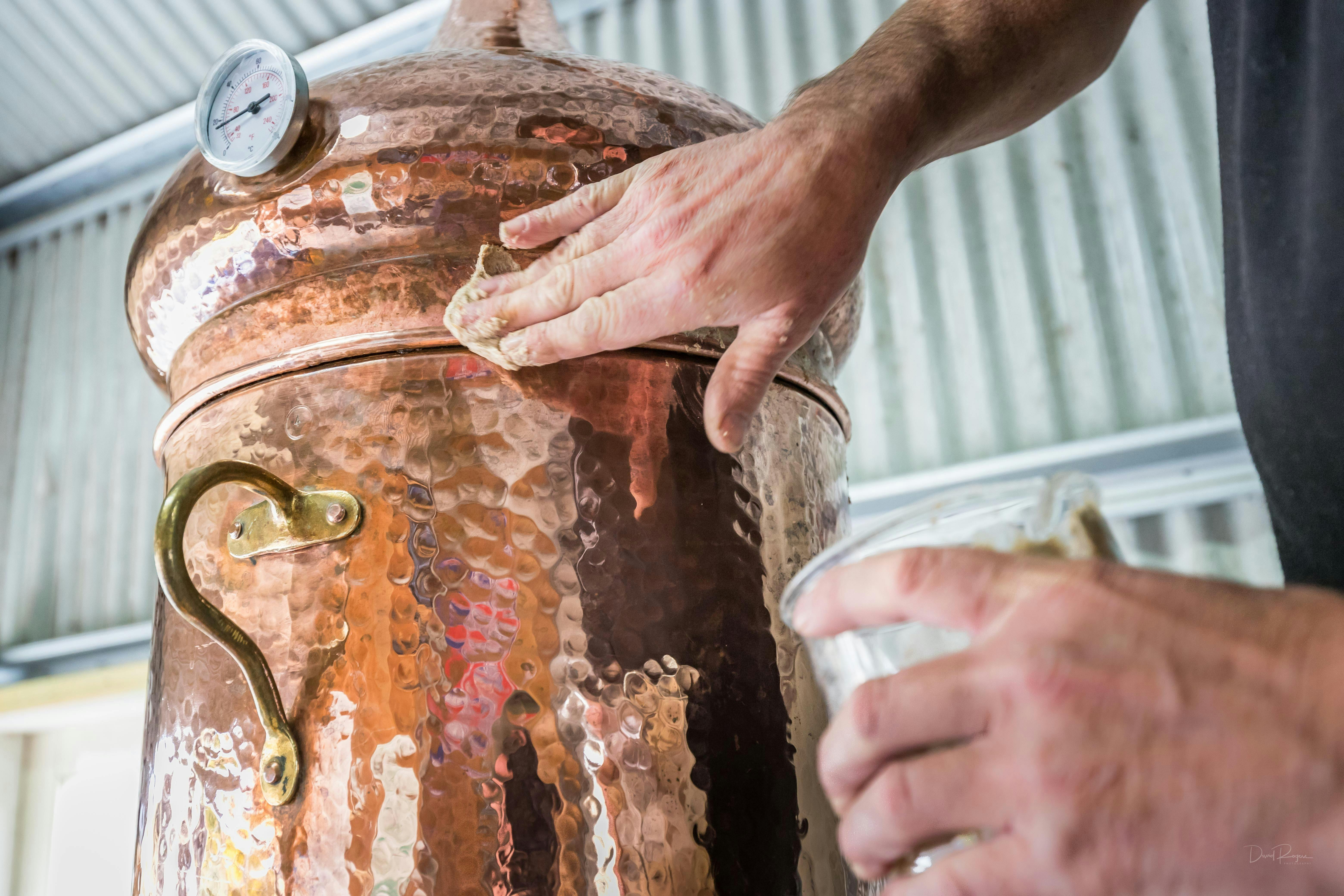 Man sealing a small copper still with rye flour paste