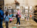 People looking at photos hanging on a wire frame