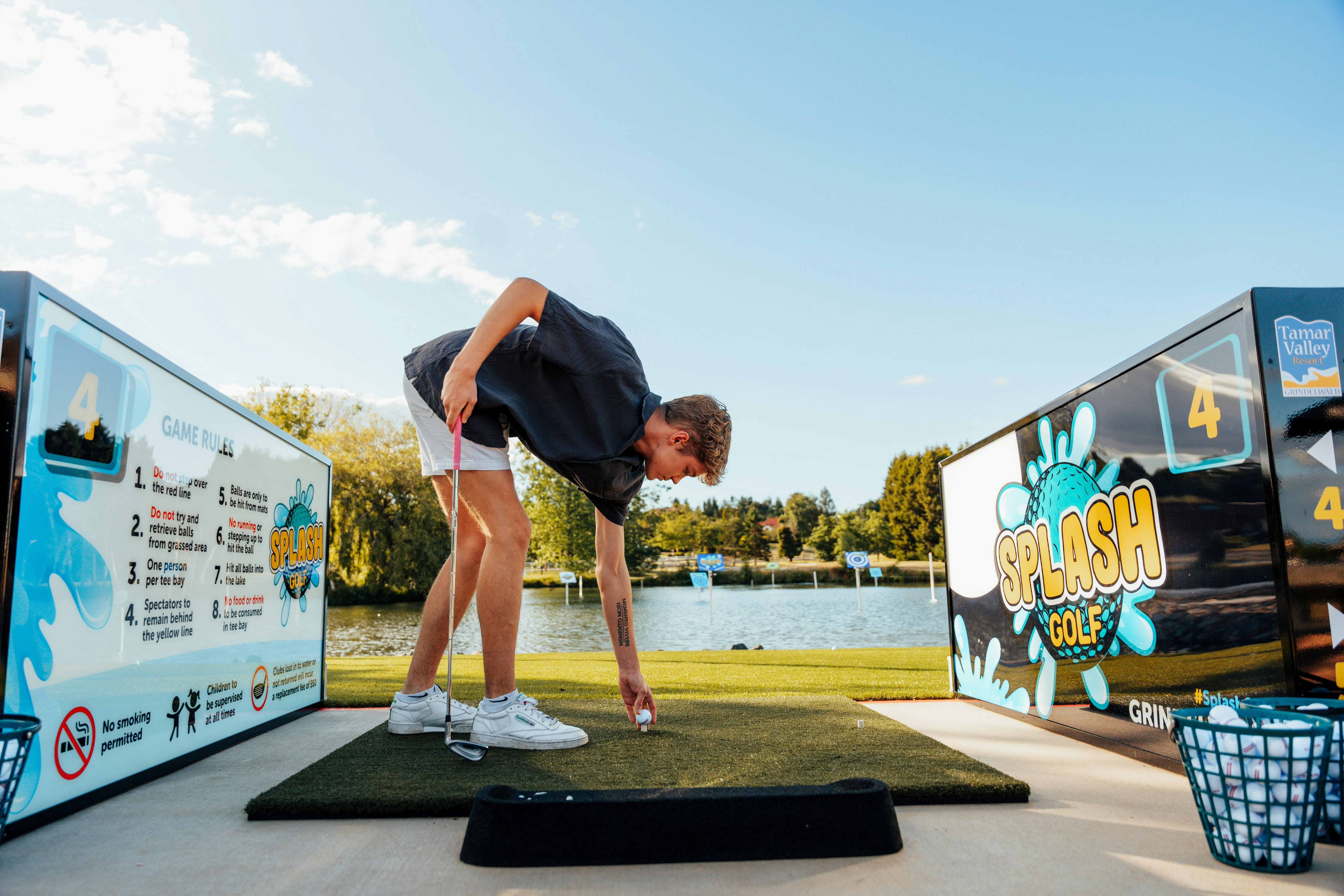 Man teeing off to play Splash Golf. View of lake and targets in the back ground.
