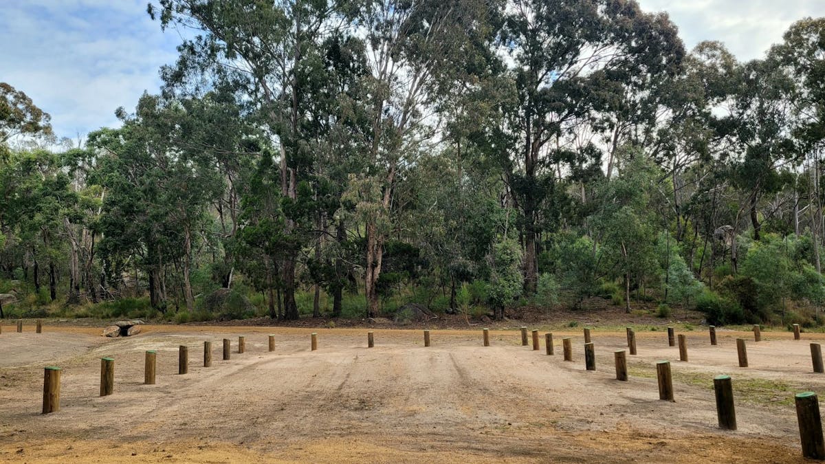 A flat, dirt, camp site marked by wooden fence posts.