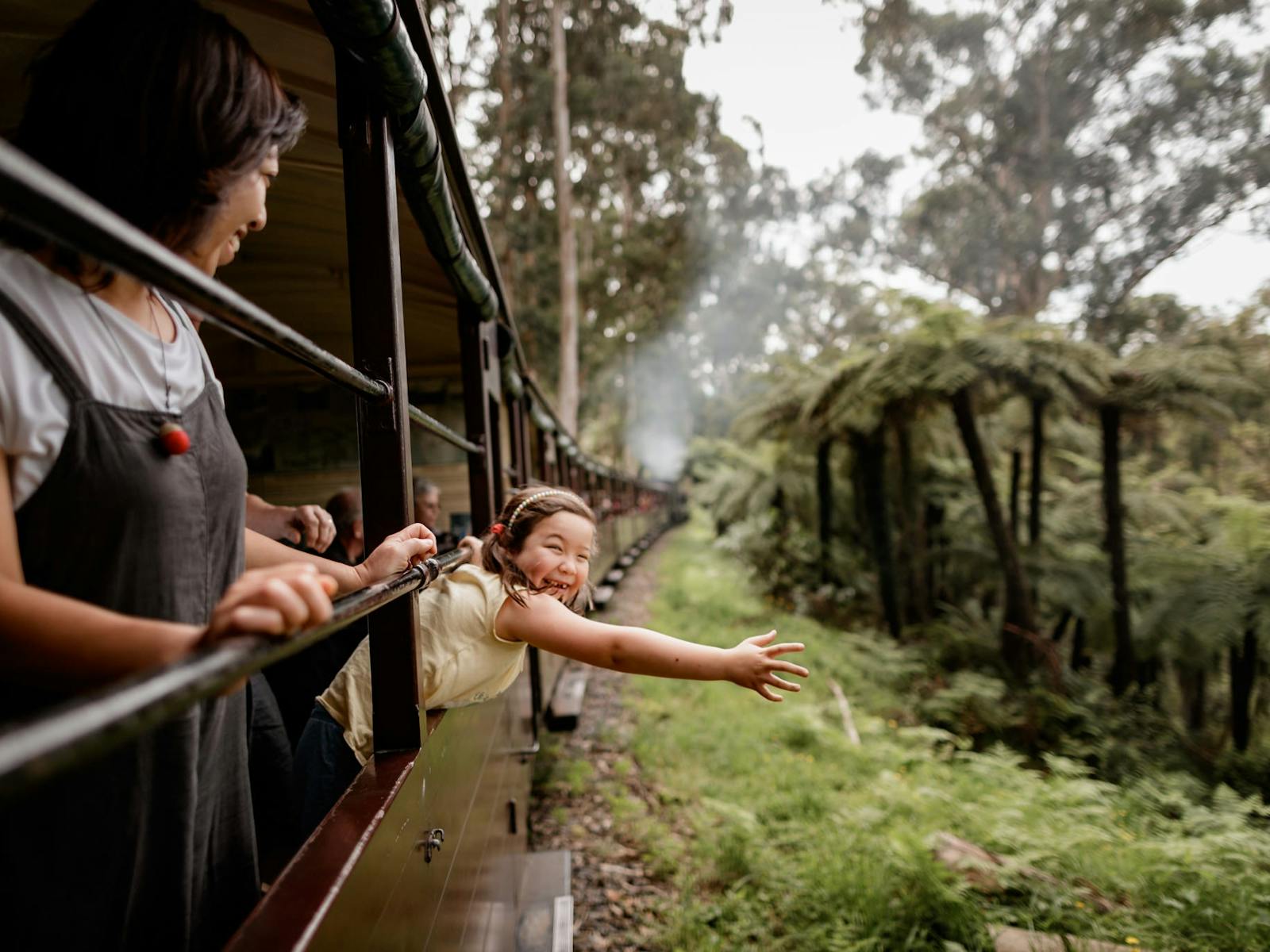 Girl smiling and stretching arm out of carriage