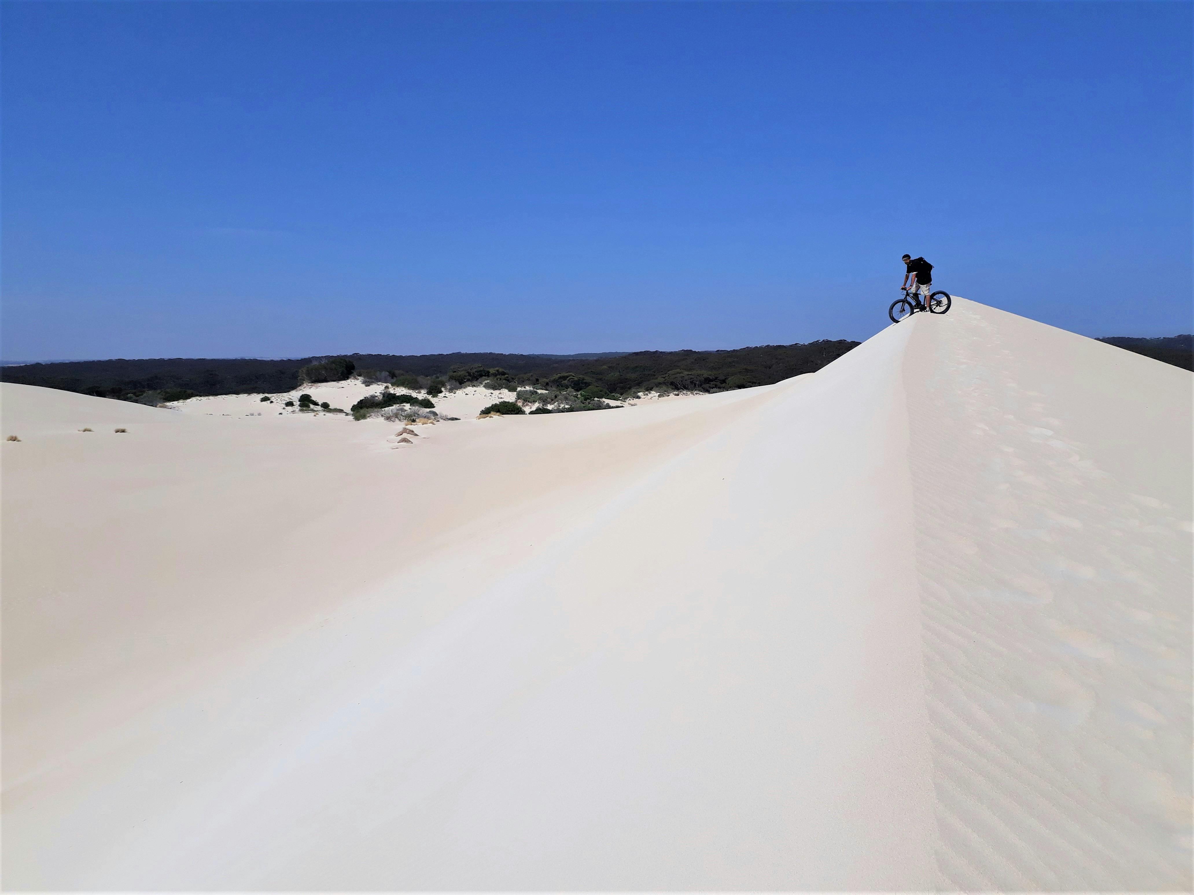 Man abotu to ride down large sand dune