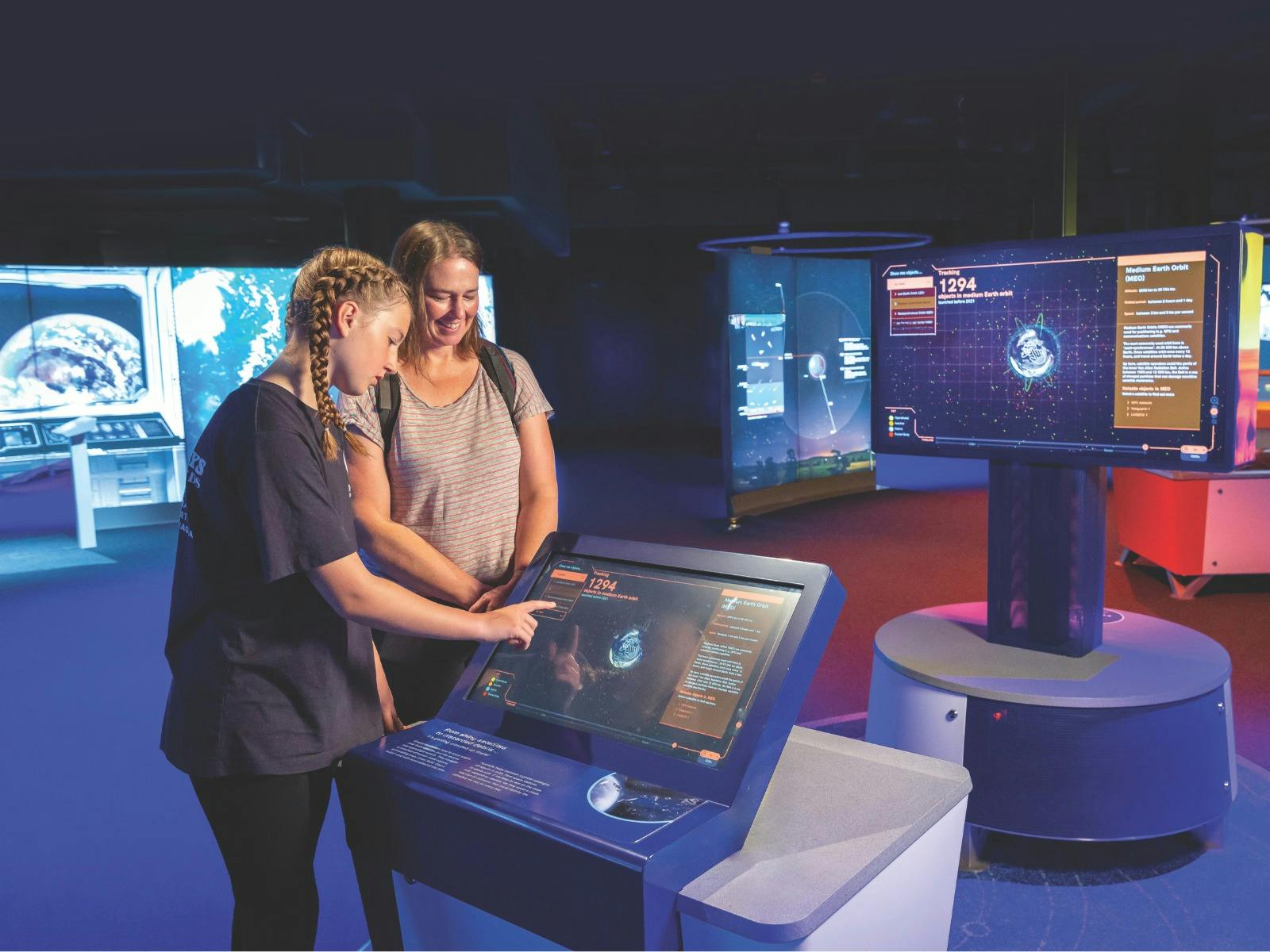 Two people interact with a space exhibit at the Australia in Space museum exhibition