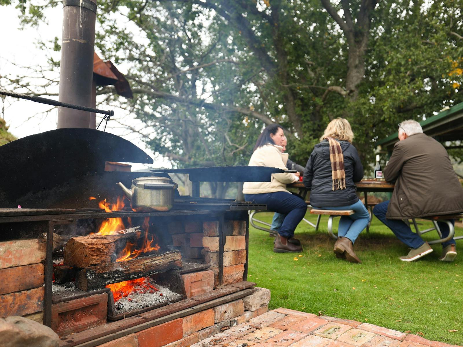 people sitting at outside tale with campfire