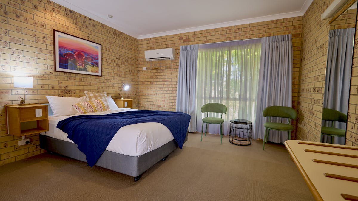 Comfortable room featuring a queen bed, seating area and bright local artwork