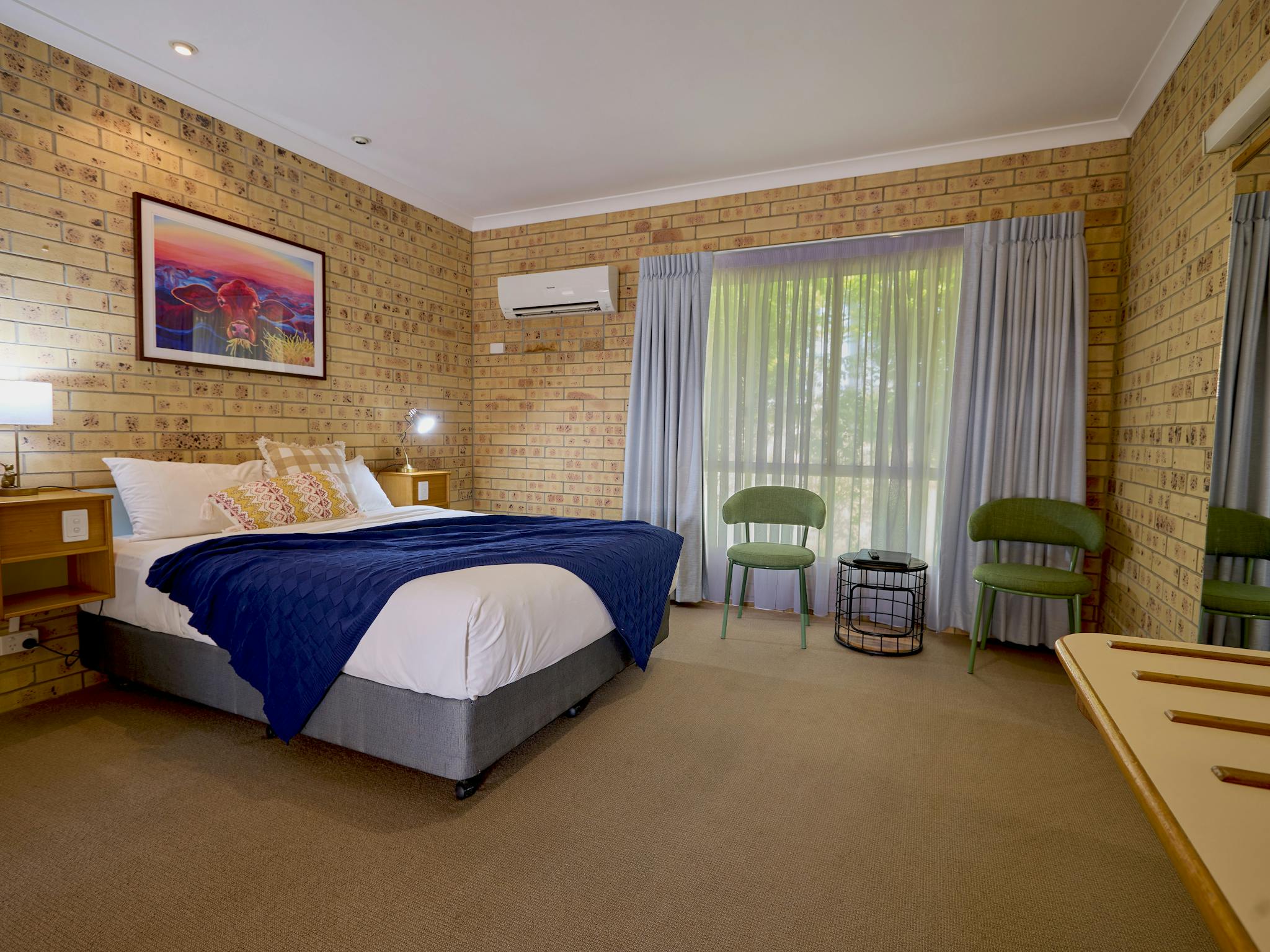 Comfortable room featuring a queen bed, seating area and bright local artwork Comfortable room featuring a queen bed, seating area and bright local artwork