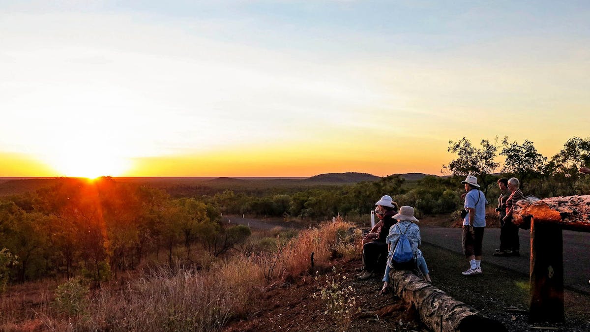 Hikers resting on the side of the road admiring the sunset