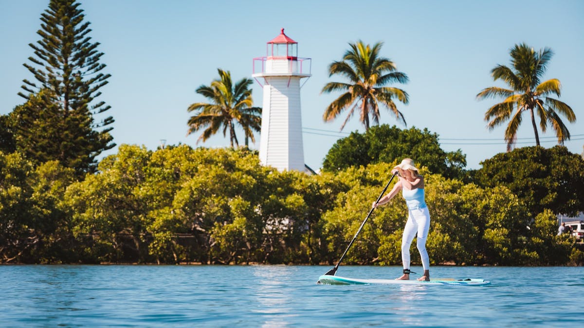 Woman on SUP with Cleveland Lighthouse and mangroves in the background, Redlands Coast fun Woman on SUP with Cleveland Lighthouse and mangroves in the background, Redlands Coast fun