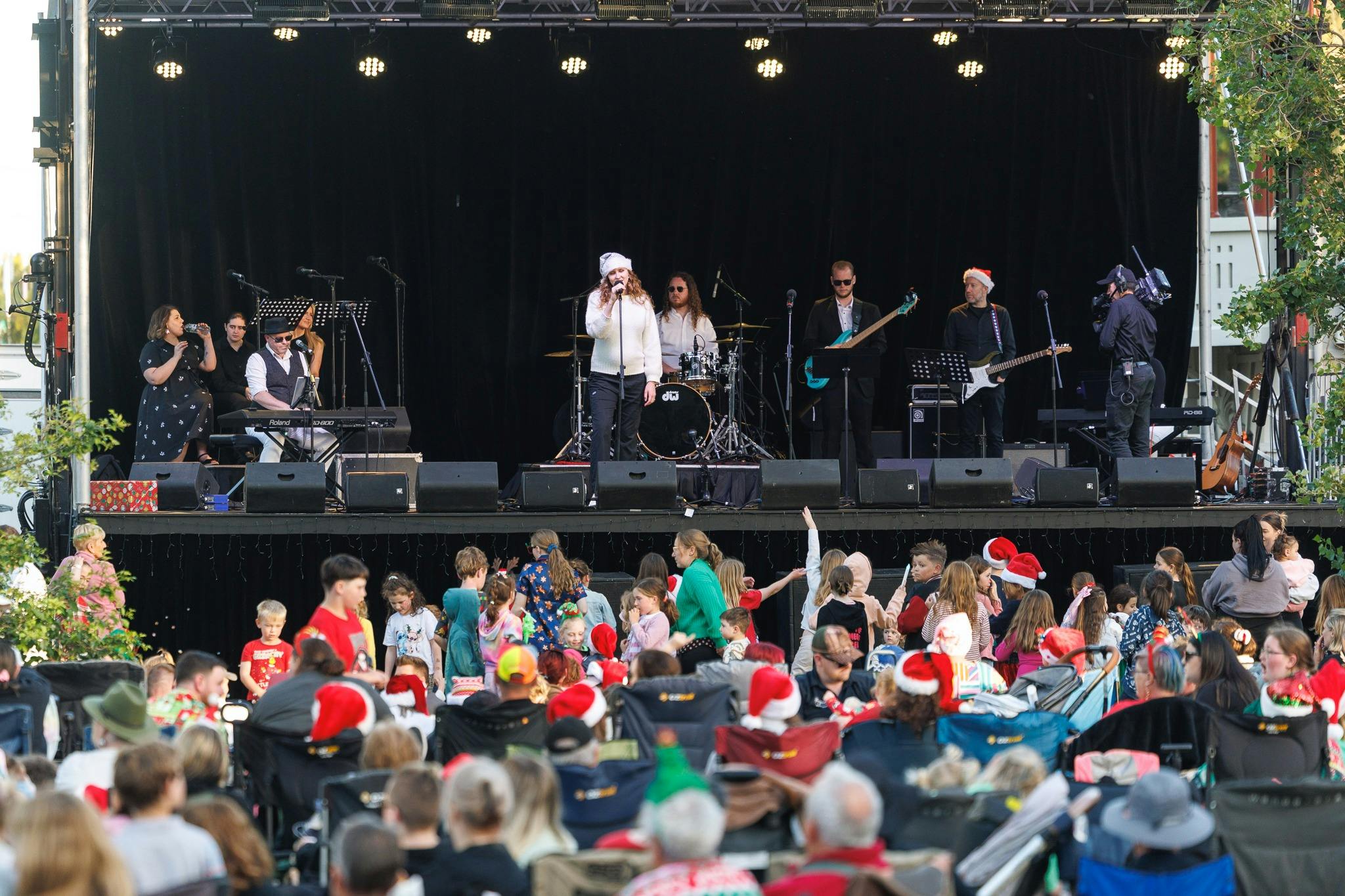 Grace Bulter performing at Carols by Candlelight with a  crowd of the children at the front of stage