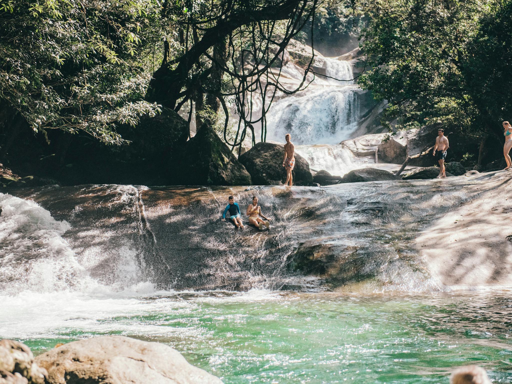 Two guest slide down the natural rock water slide at Josephine Falls in Tropical North Queensland Two guest slide down the natural rock water slide at Josephine Falls in Tropical North Queensland