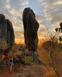 A woman walks towards balancing rock at sunset in Chillagoe-Mungana Caves National Park