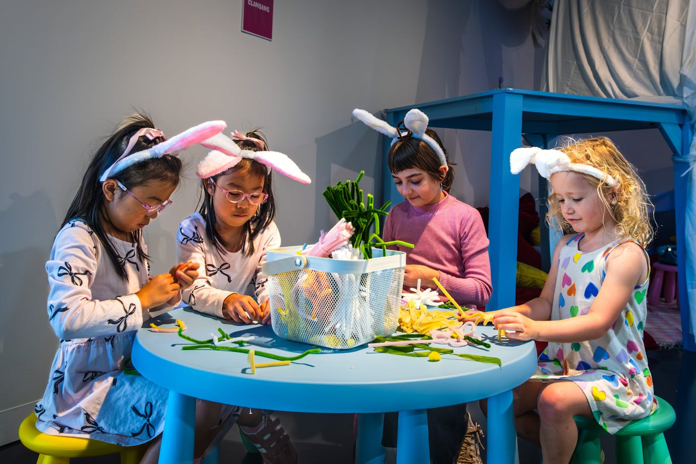 Four children creating objects out of colourful pipe cleaners