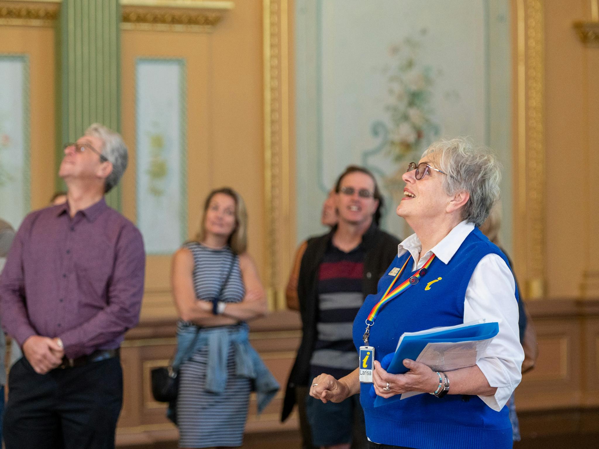 Guide showing engaged visitors the ornate plasterwork, murals and gold leaf work of the hall.