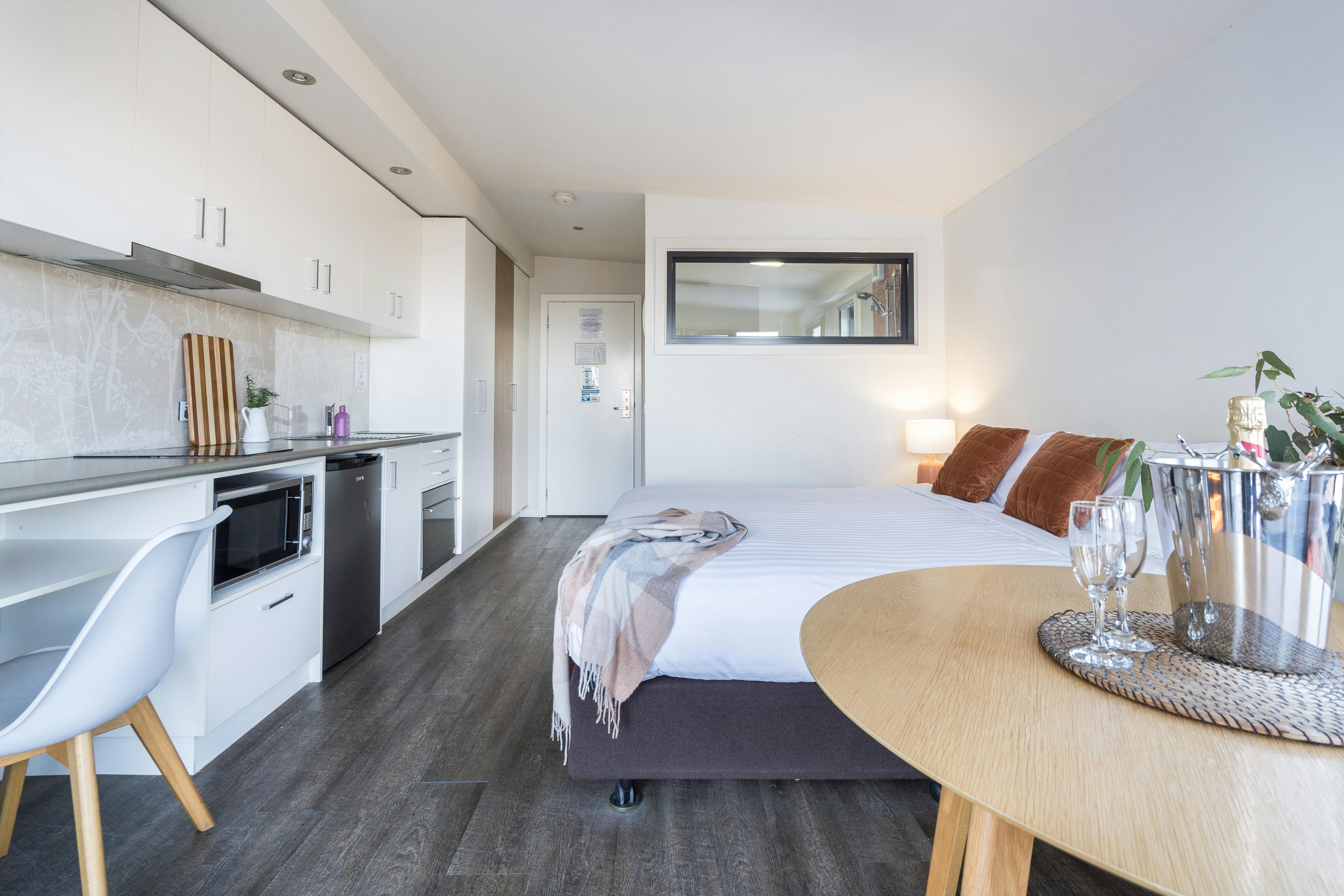 Kitchenette, king bed, table within the studio apartment