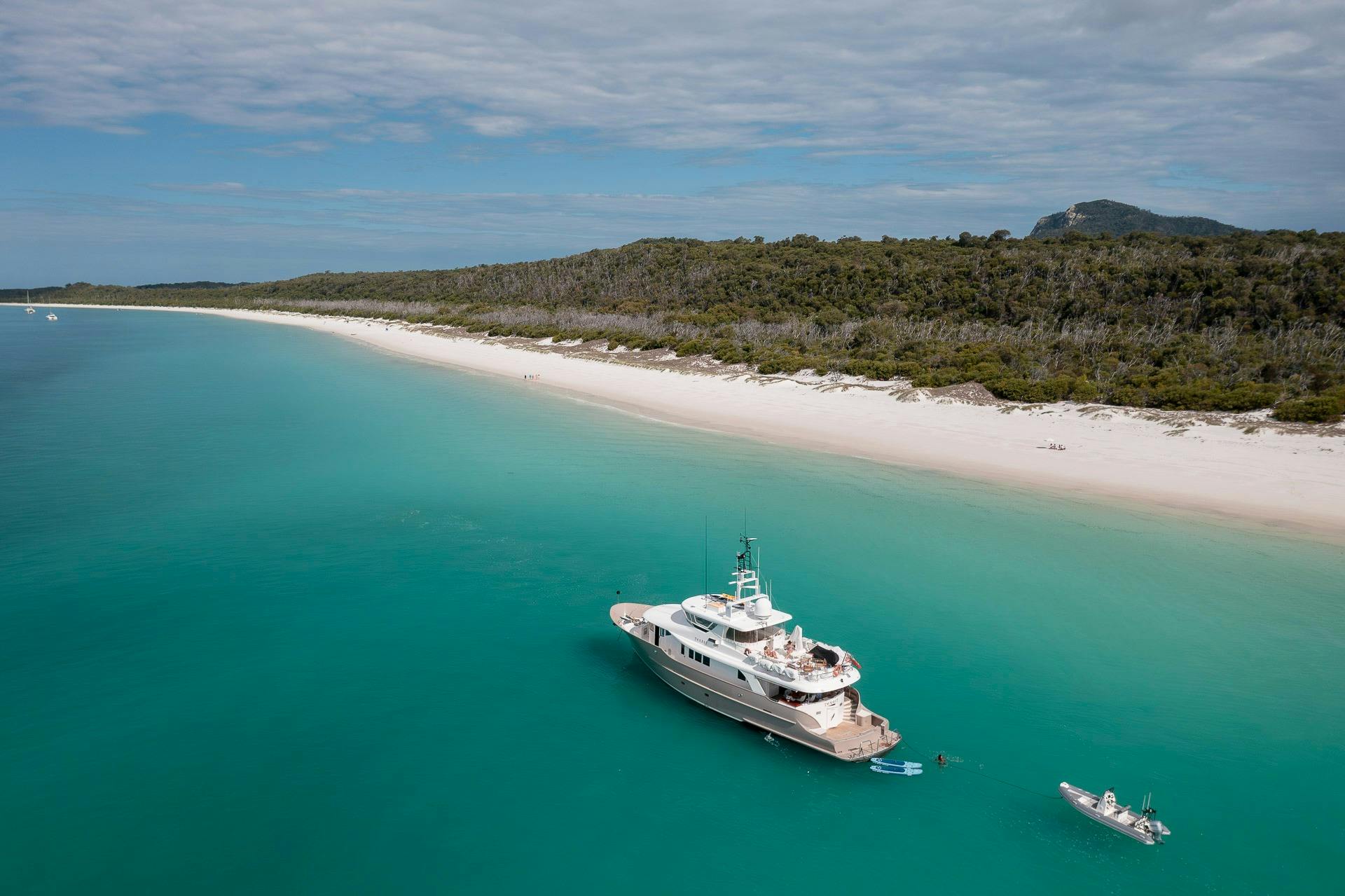 Drone aerial image of Texas T motor yacht moored next to Whitehaven beach, blue ocean