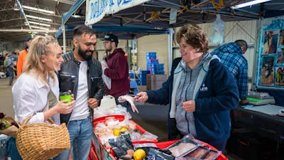 shoppers selecting fresh seafood from local farmers market in Canberra