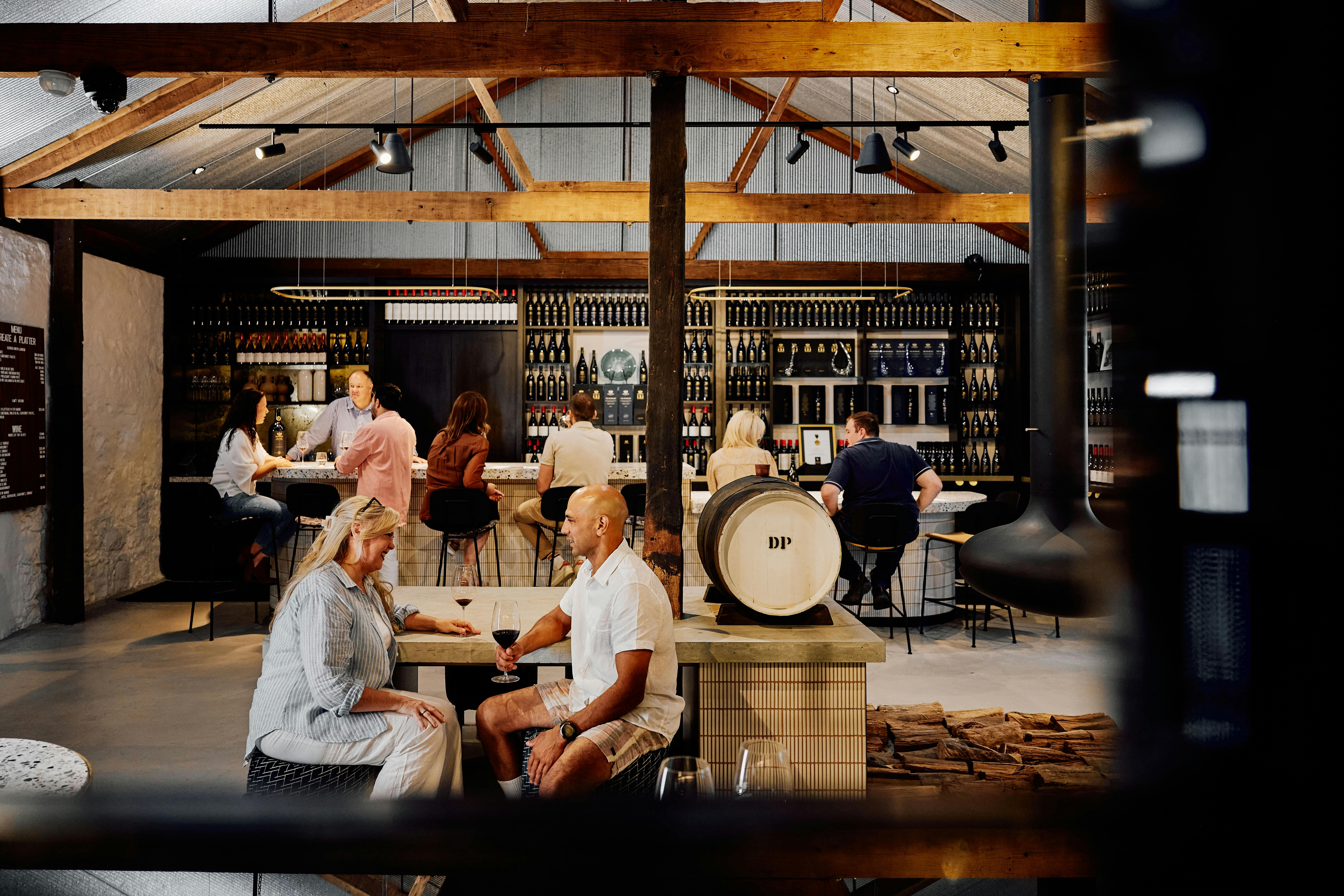 Guests sitting at the tasting bar and tables at Krondorf Cellar Door with modern stone & rustic wood