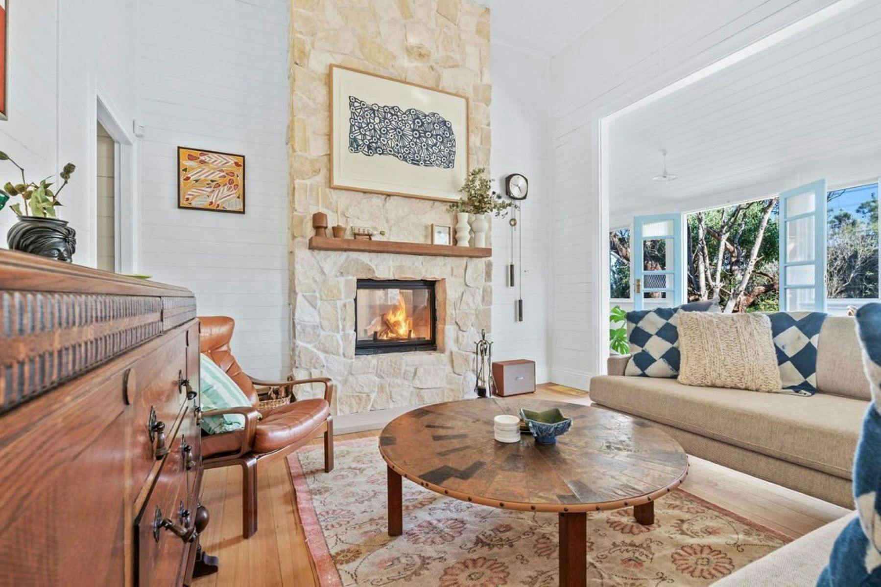 Image of fireplace. Sandstone all around fireplace. Comfortable unique furnishings surround  fire.