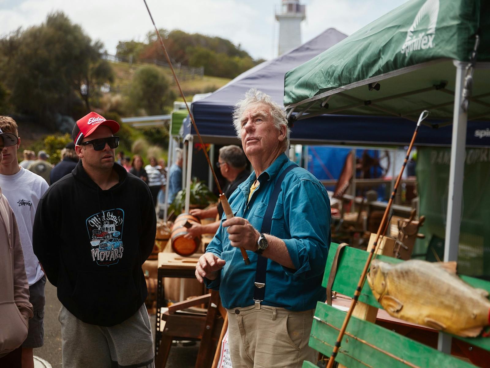 man holding a Fishing Rod and addressing a group of people