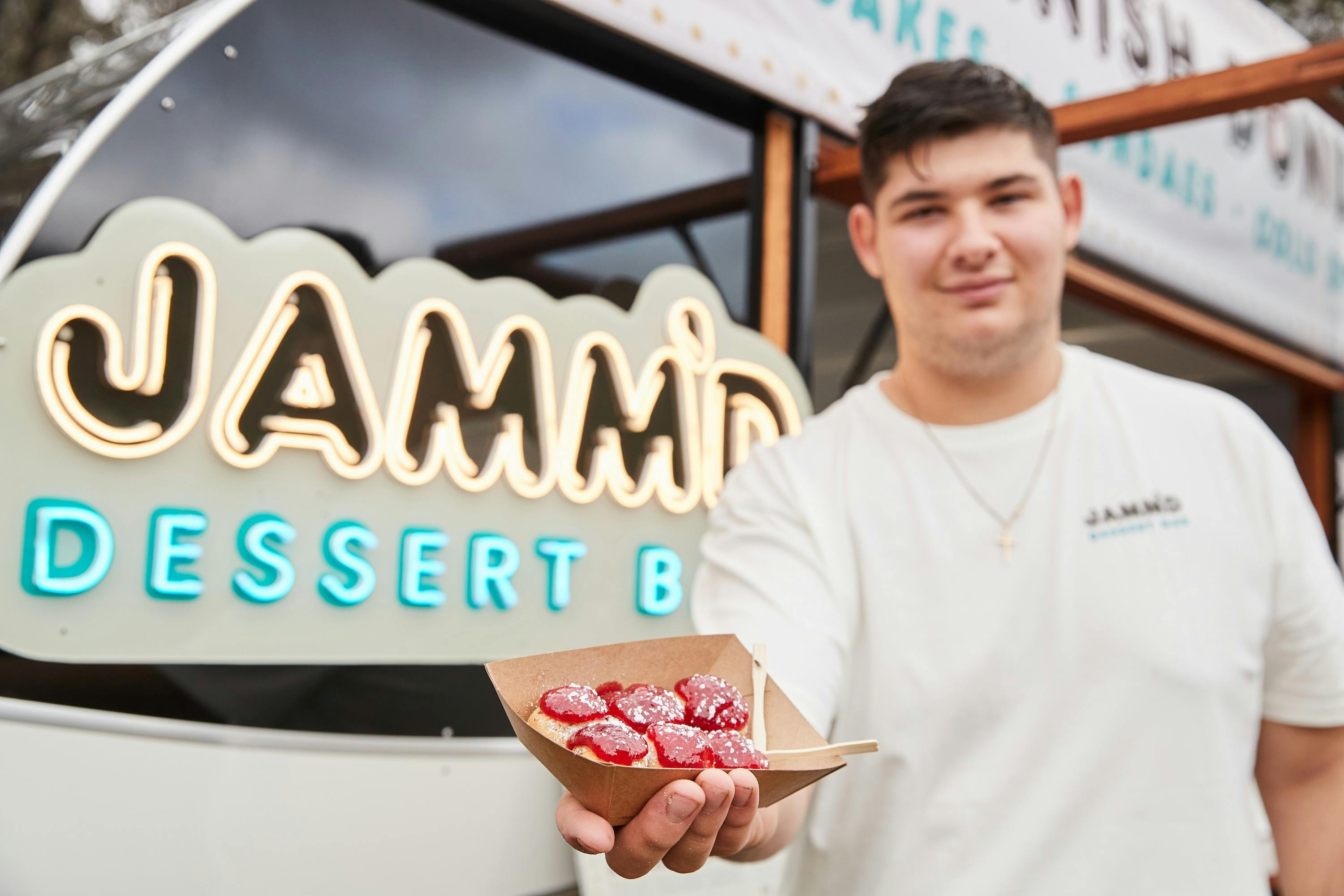 Man holding a tray of jam donuts from Jamm'd Dessert Bar food truck at Grampians Grape Escape