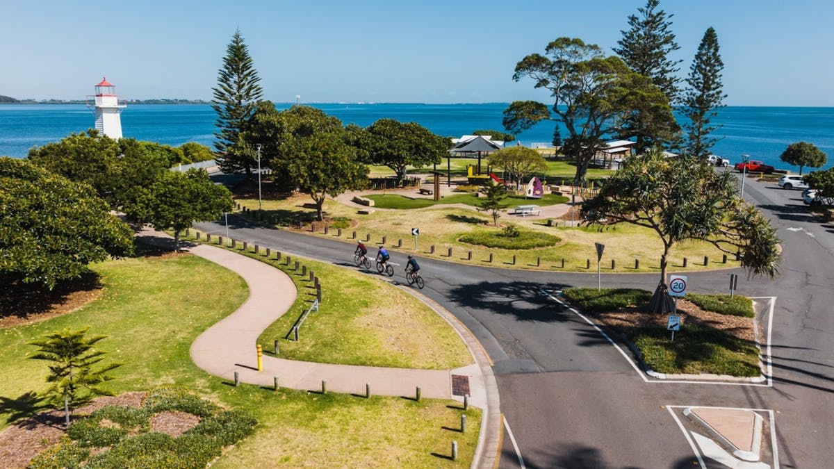 Aerial of Cleveland Point with cyclists, playground, lighthouse; sunny calm waters fun fact: visit!