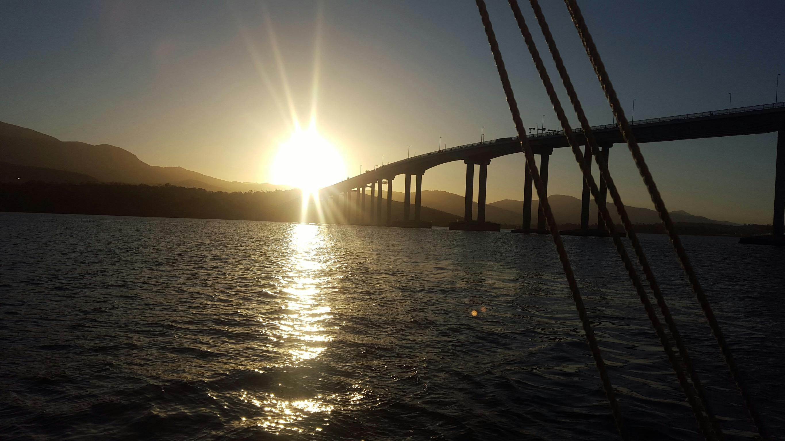 The sun as it passes the Tasman Bridge from onboard SV Rhona H