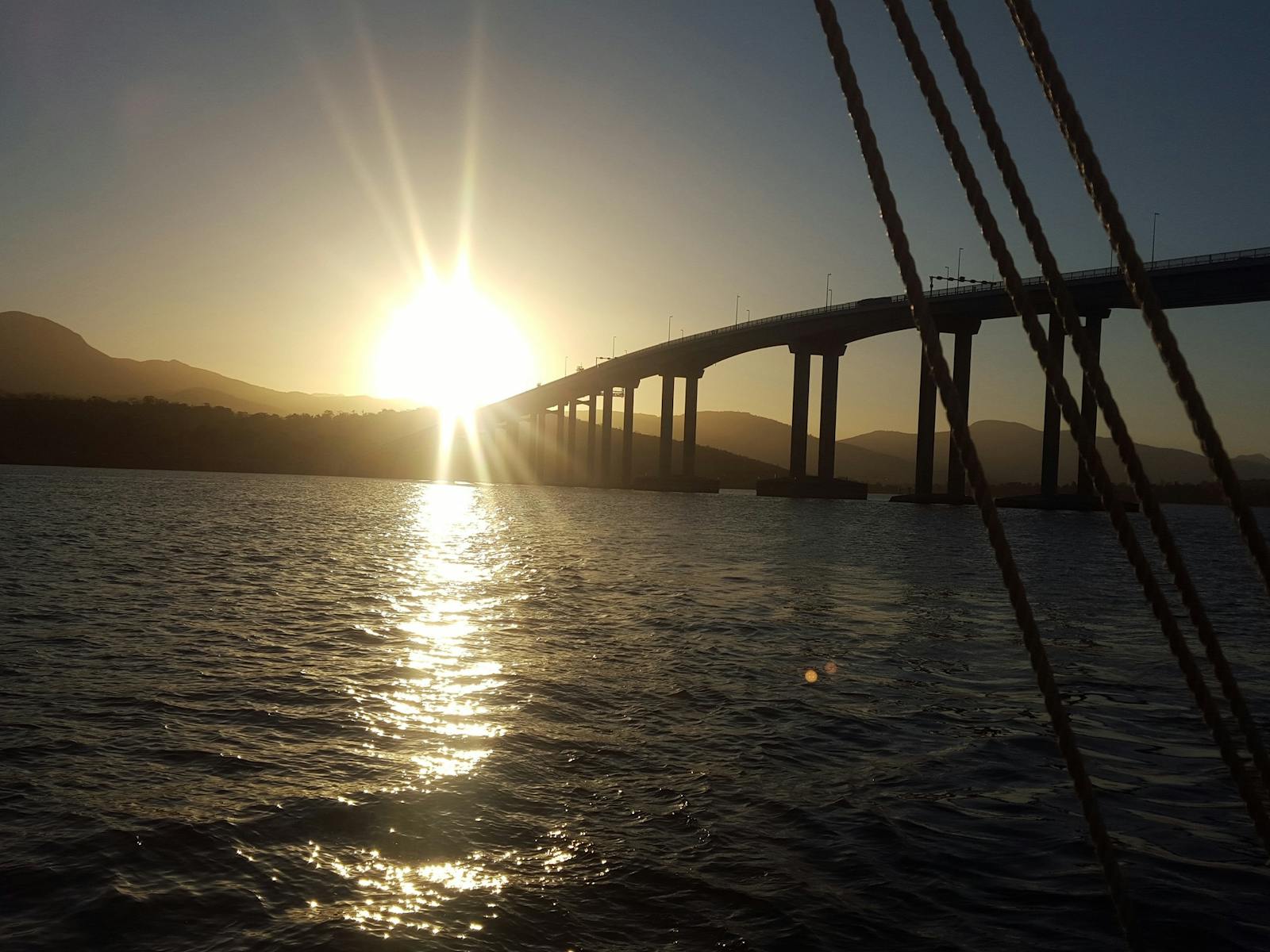 The sun as it passes the Tasman Bridge from onboard SV Rhona H