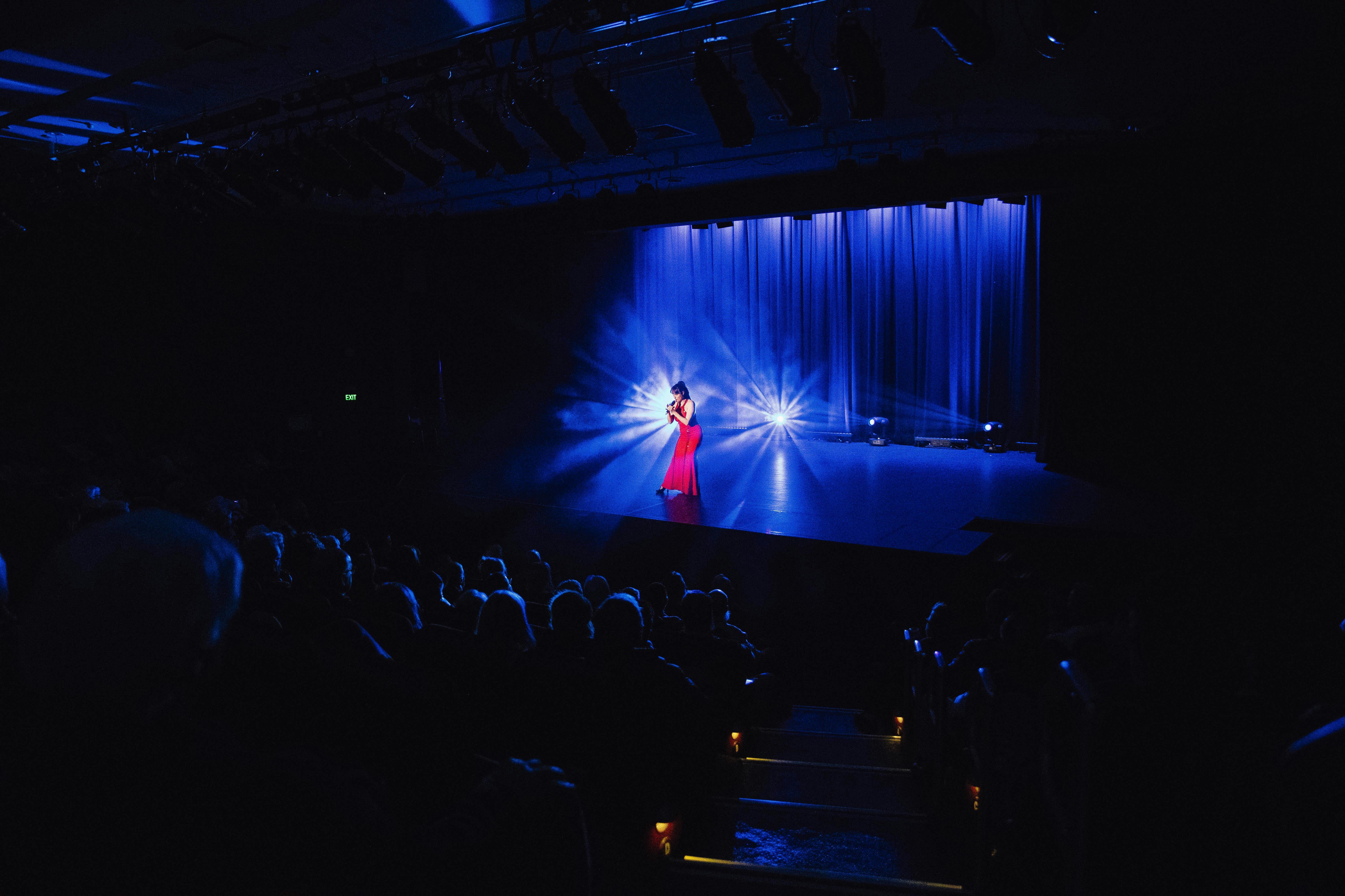 A singer holds the attention of the audience. There is lighting behind the singer on the stage