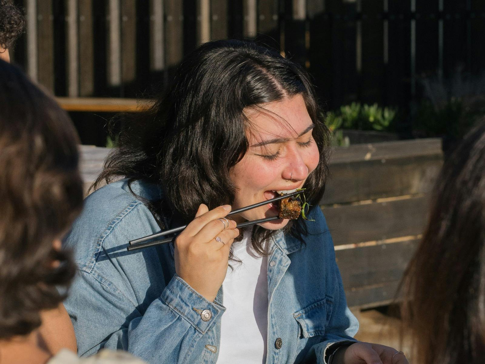 Customer enjoying Thai food with chopsticks outdoors at Easy Tiger in St Helens.