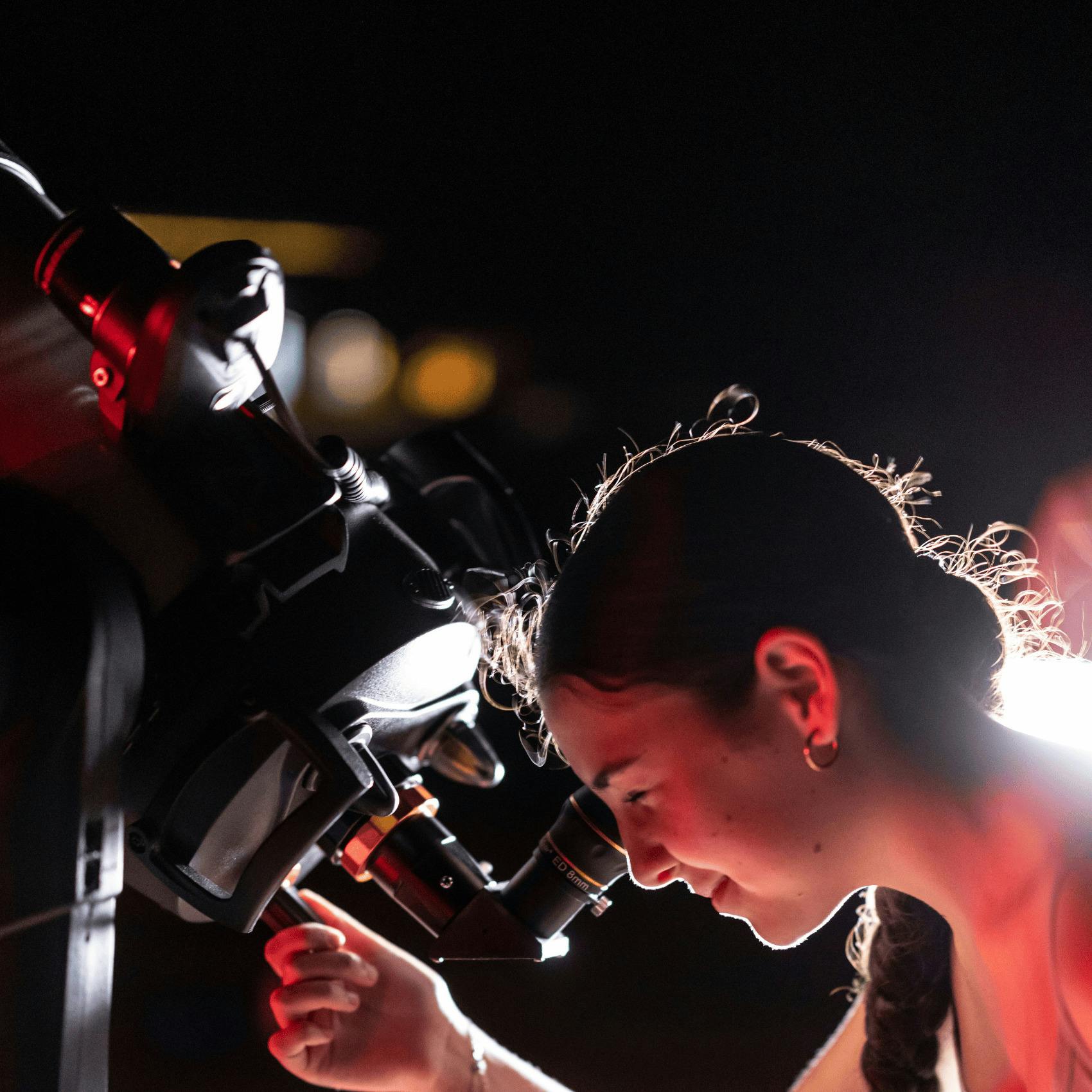 Young woman looking through a telescope