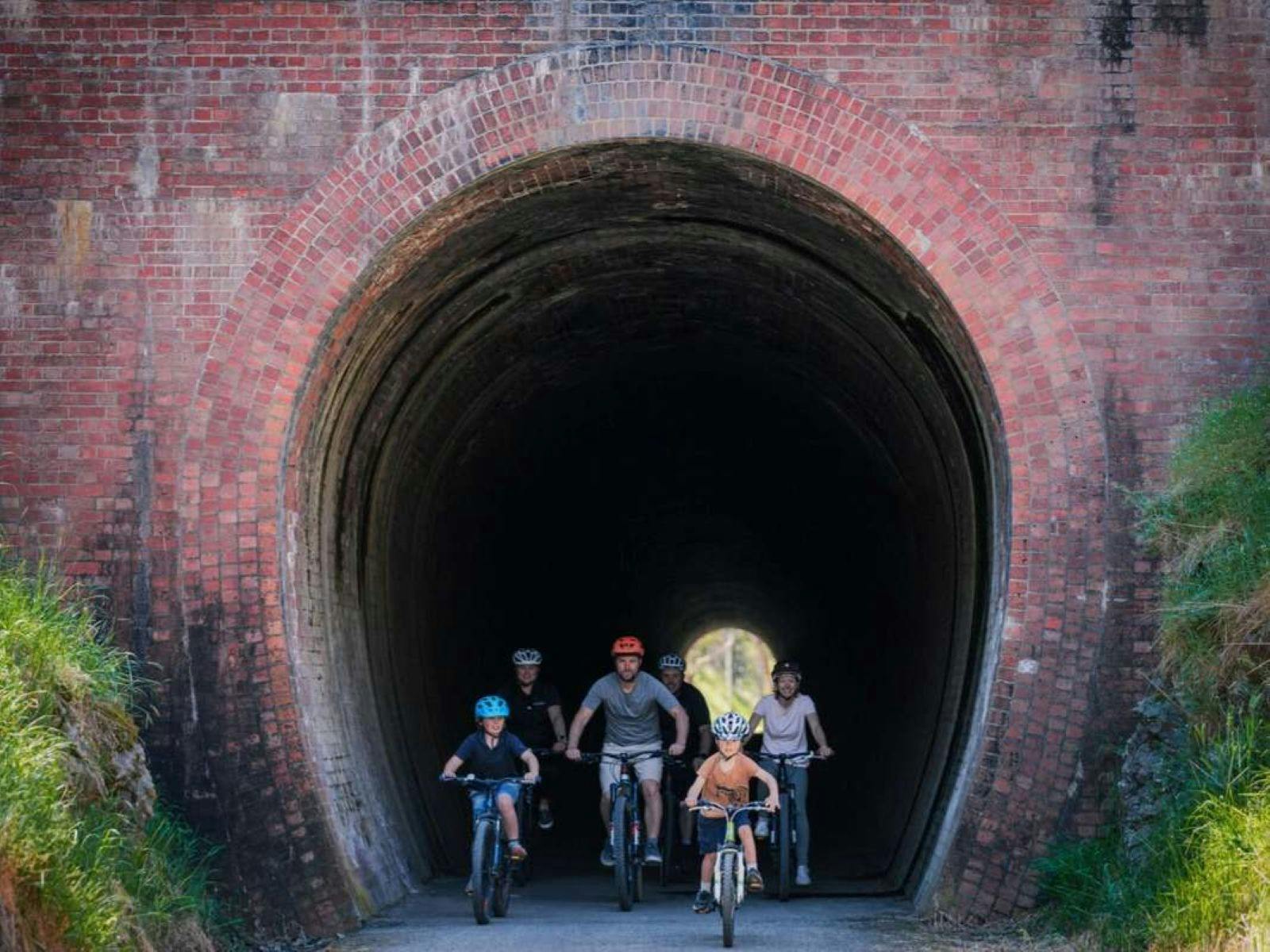 A family cycles with Double Black Alpine guides through the brick-lined Cheviot Tunnel on the Great